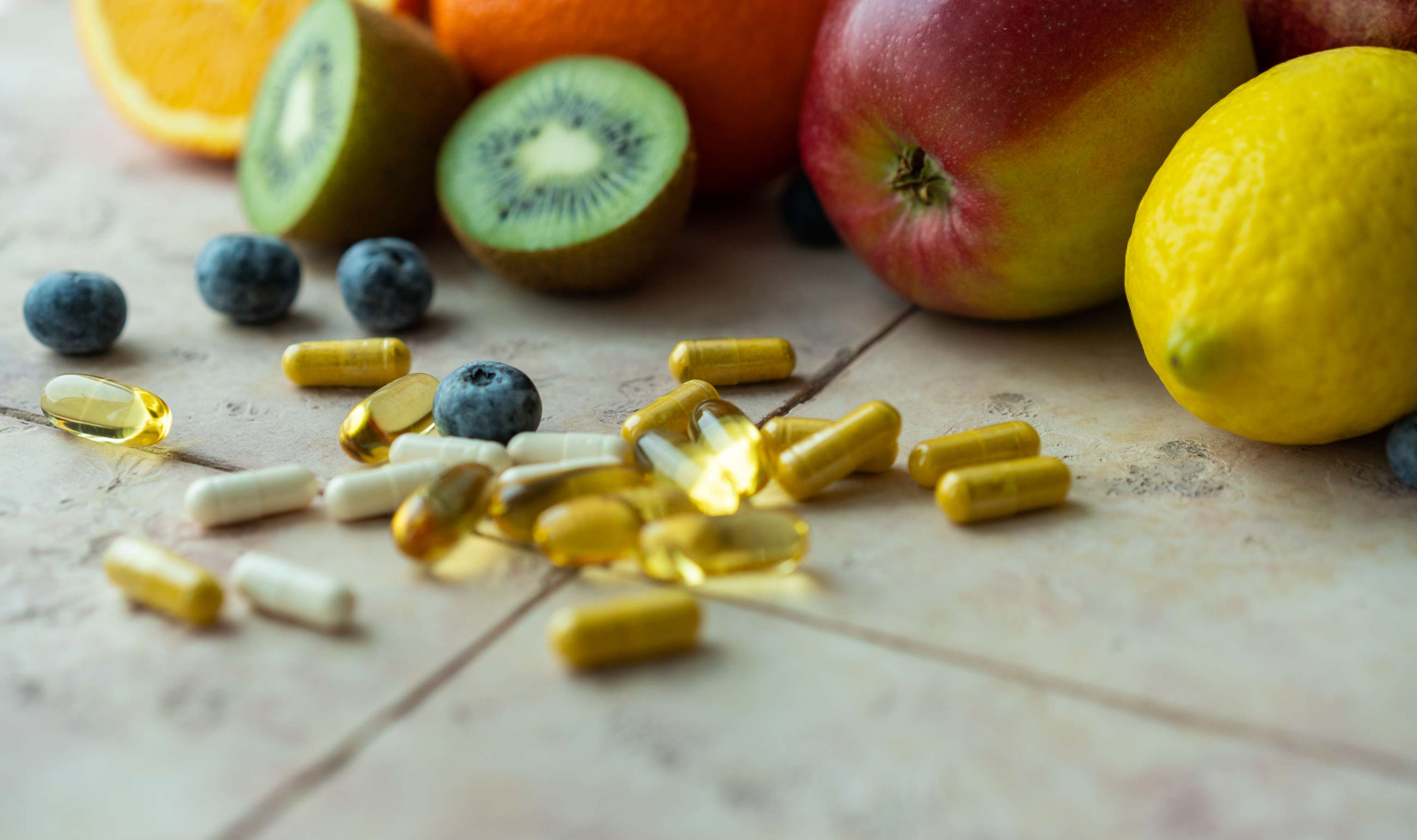 Natural fruits and multivitamin capsules. Natural and synthetic sources of vitamins Close up fruit and vitamin capsules