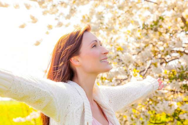 carefree Woman spreads her arms. Nature with trees in background