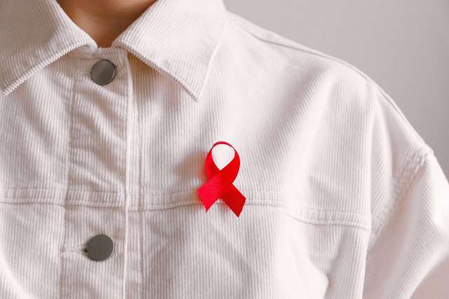 mann-das-bewusstsein-symbol-band-3900469 Una persona in camicia bianca indossa un Red Ribbon, simbolo di solidarietà con le persone infette da HIV e i malati di AIDS.