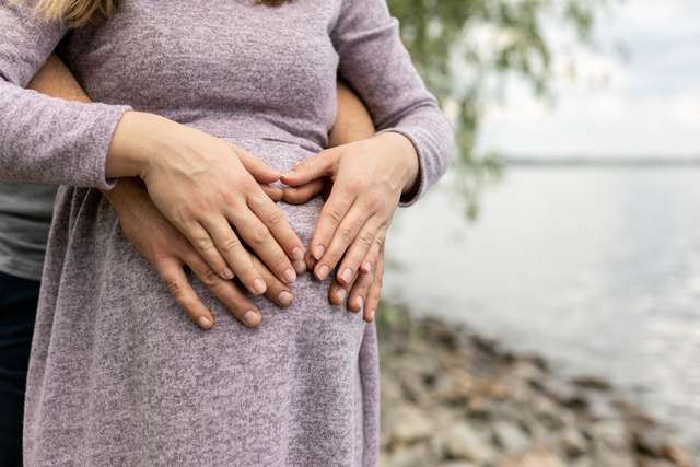 Pair of hands holding pregnant young women belly A couple holds the pregnant woman's belly.