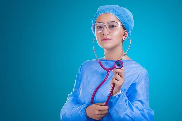 pixabay.com @ voltamax (CC0 Creative Commons) Um grande plano de uma mulher num vestido de hospital segurando um estetoscópio.