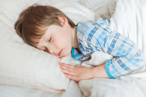 Beautiful little boy sleeping in bed Little boy lying in bed with eyes closed.