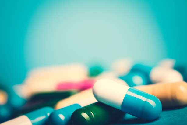 Farmaci e antibiotici verdi e gialli su sfondo blu. Medicinali: compresse o capsule verdi e gialle su sfondo blu con spazio per la copia. Medicinali per la guarigione in contenitori per la salute. Antibiotici