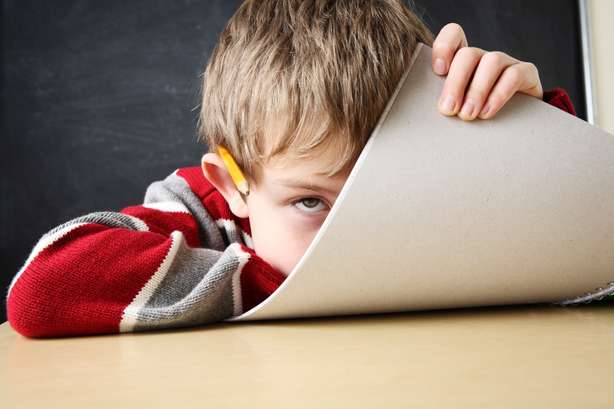 verveelde student Verveelde leerling houdt een notitieboekje voor zijn gezicht.