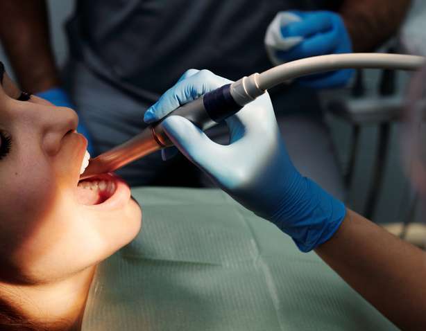 Una persona con guantes de látex azules revisa los dientes de un paciente Grabación de un examen dental