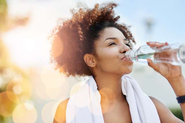 Maintaining good hydration also supports healthy weight loss. Cropped shot of a young woman enjoying a bottle of water while out for a run. Junge Frau trinkt aus einer Wasserflasche.