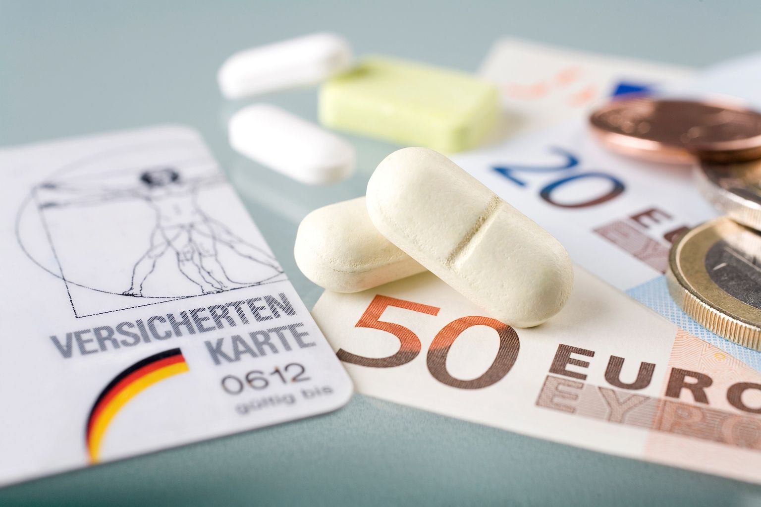 Un gros plan sur une carte d'assuré d'Allemagne, de l'argent liquide et des médicaments.