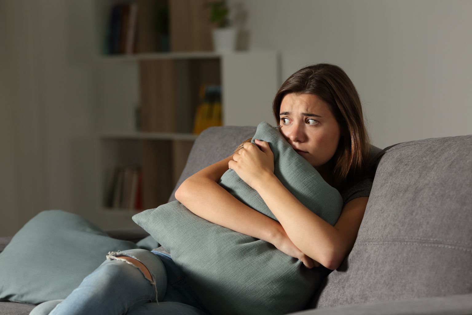 Adolescentes con miedo a casa con almohadas sentados en un sofá en la sala de estar 