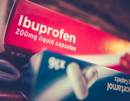 Boîte d'analgésiques prescrits sur ordonnance (ibuprofène et paracétamol) sur une armoire à la maison.